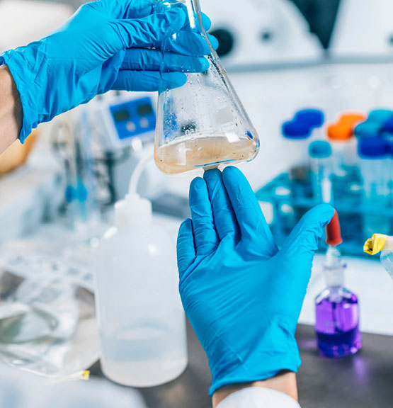 Ein Techniker, der Schutzhandschuhe trägt, untersucht die Wassertrübung in einem Labor.